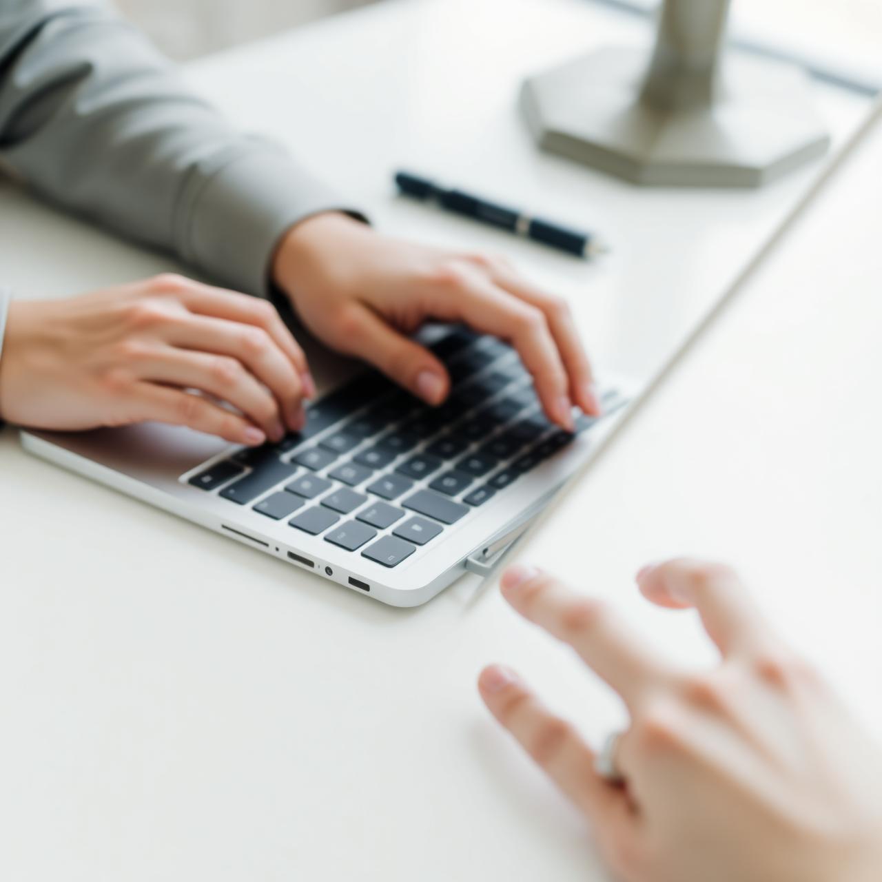 Hands typing on a laptop keyboard